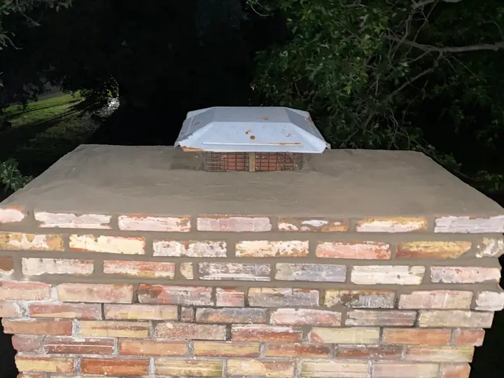 Rebuilt chimney crown with a new cap at dusk