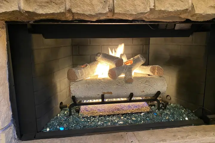 Vented gas log set burning in a brick fireplace